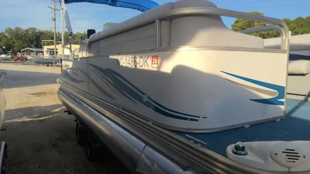 Slide: The Image of A 2008 Manitou OASIS 20 pontoon boat with blue accents, parked on a trailer. - 4