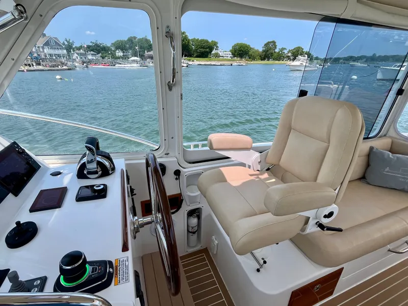 Slide: The Image of 2019 MJM 35z boat helm with beige seating, overlooking serene waterfront. - 28