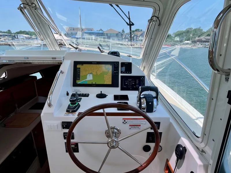Slide: The Image of Helm of 2019 MJM 35z boat with navigation display, steering wheel, and marina view. - 27