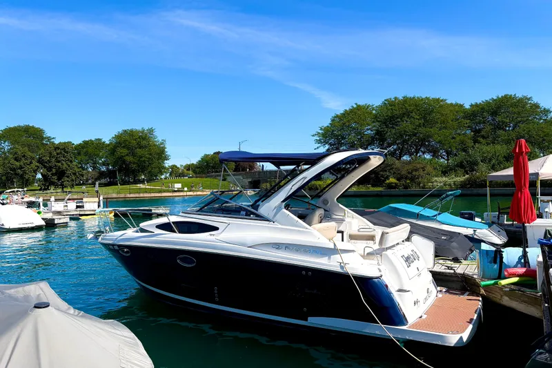 Slide: The Image of 2011 Regal 2860 Window Express boat docked on a sunny day, surrounded by lush greenery. - 1