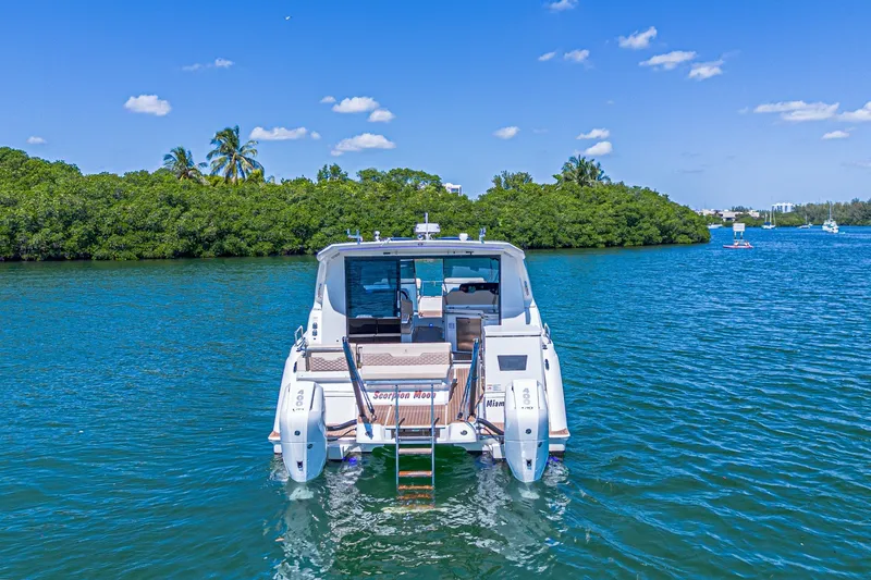 Slide: The Image of 2024 Aquila 36 Sport yacht on serene blue water with lush green backdrop. - 5