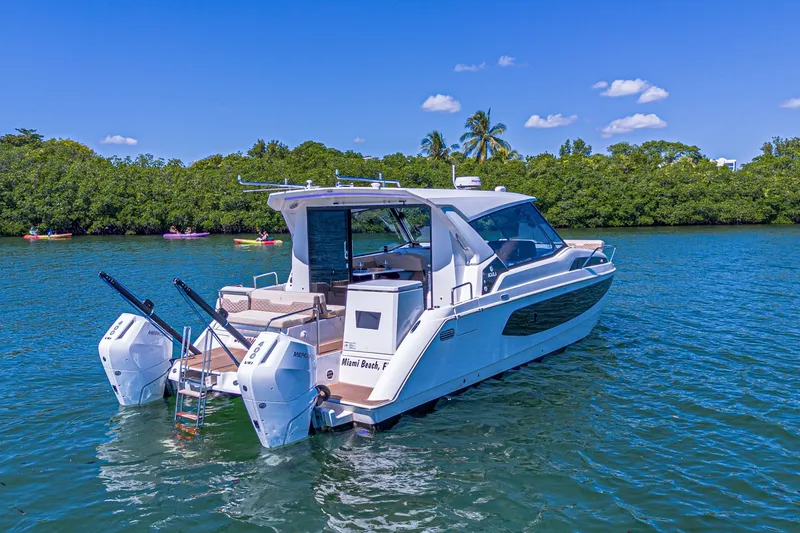 Slide: The Image of 2024 Aquila 36 Sport boat on water, lush greenery background, clear blue sky. - 6