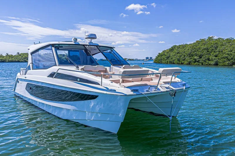 Slide: The Image of 2024 Aquila 36 Sport boat on serene water with lush greenery background. - 2