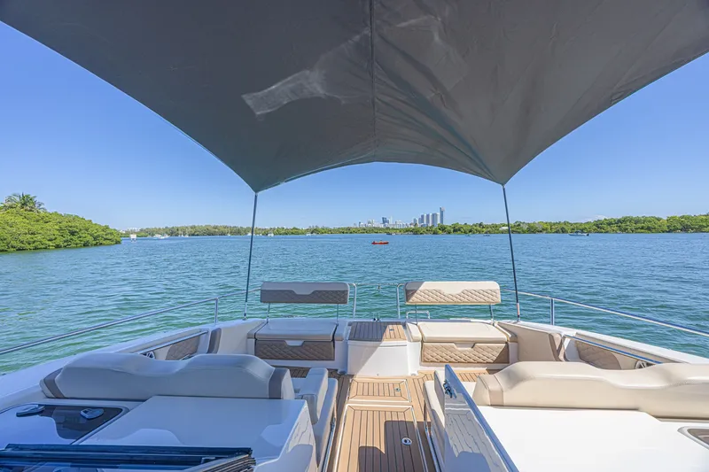 Slide: The Image of 2024 Aquila 36 Sport yacht with canopy, overlooking serene water and distant city skyline. - 19