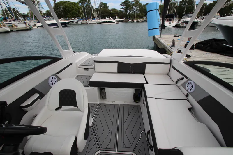 Slide: The Image of 2025 Monterey M-22 boat interior with white seating, docked at a marina. - 20