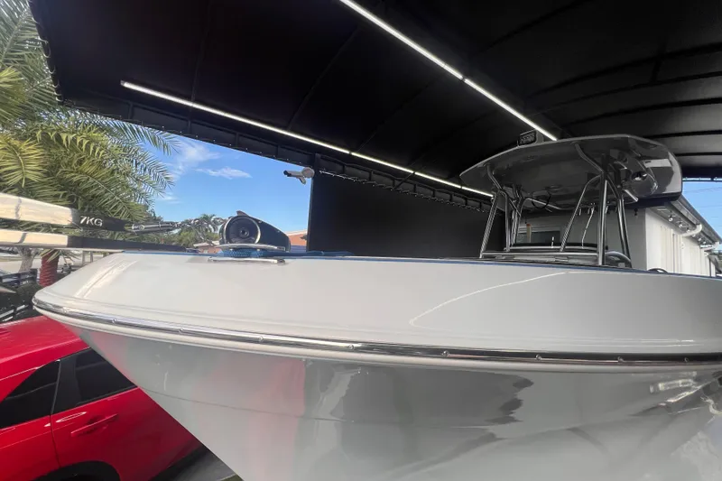 Slide: The Image of 2022 Aquasport 2300 Center Console boat under a canopy, with palm trees in the background. - 2