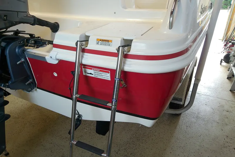 Slide: The Image of 2012 Hurricane SunDeck 217 OB boat with red and white exterior, featuring a ladder. - 16
