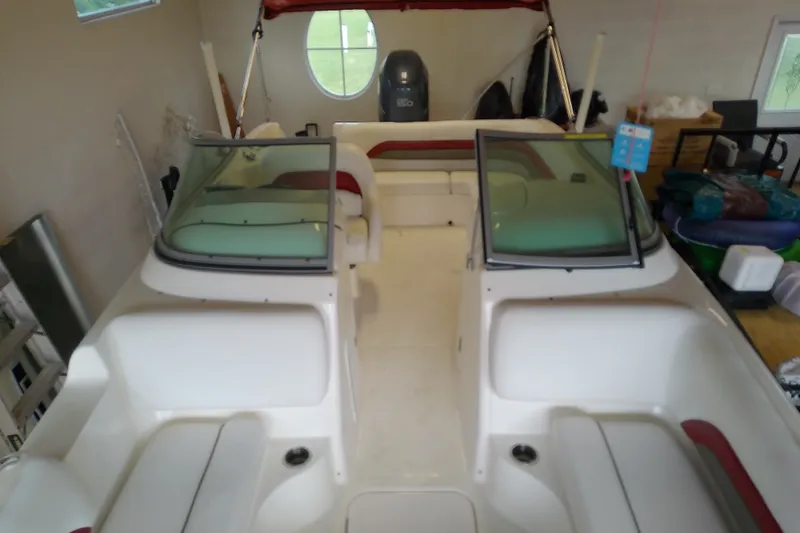 Slide: The Image of 2012 Hurricane SunDeck 217 OB boat interior with seating and windshield in a garage. - 21