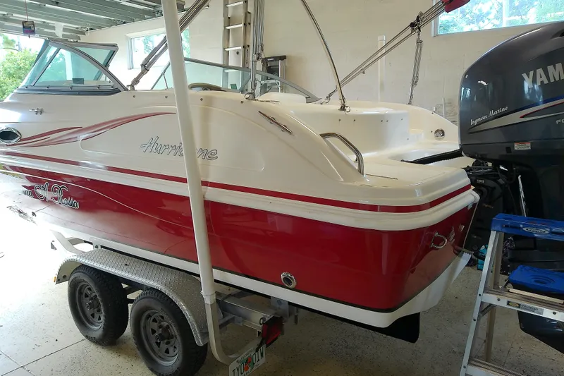 Slide: The Image of 2012 Hurricane SunDeck 217 OB boat in garage, red and white design, on trailer. - 13