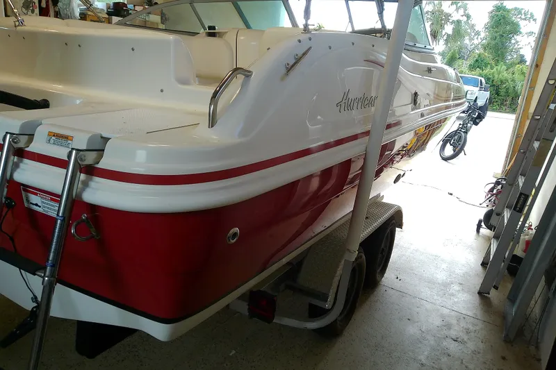 Slide: The Image of 2012 Hurricane SunDeck 217 OB boat in garage, red and white design, on trailer. - 15