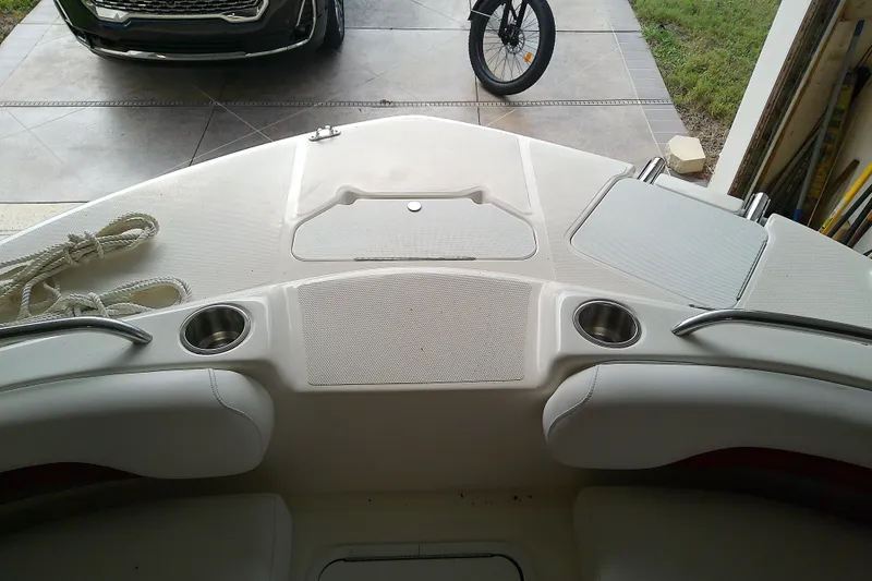 Slide: The Image of 2012 Hurricane SunDeck 217 OB boat interior with cup holders and rope, parked in a garage. - 20