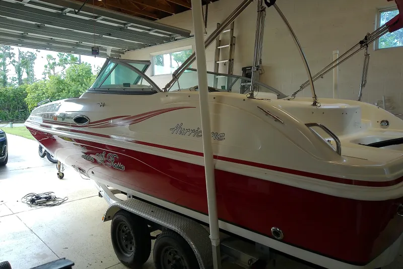 Slide: The Image of 2012 Hurricane SunDeck 217 OB boat in garage, red and white design. - 14