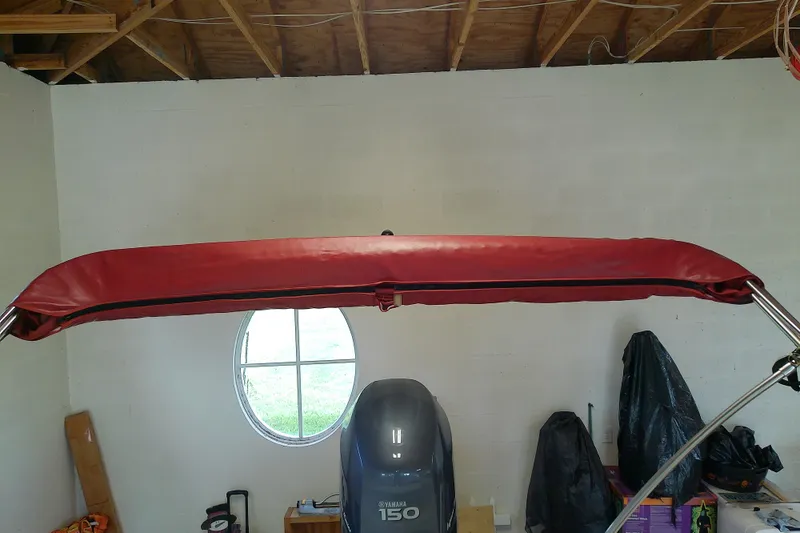 Slide: The Image of 2012 Hurricane SunDeck 217 OB with red bimini top in garage setting. - 28