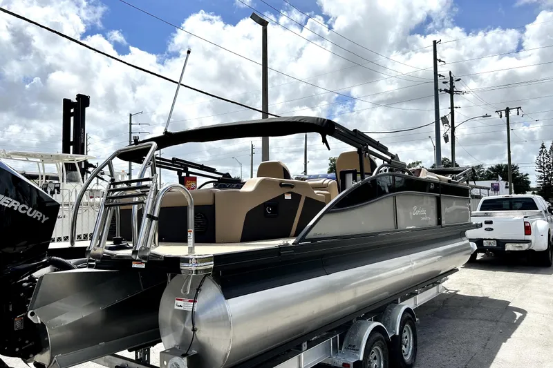 Slide: The Image of 2022 Barletta E24UC pontoon boat on trailer under cloudy sky. - 1