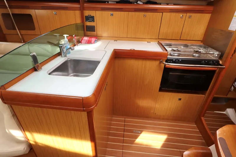 Slide: The Image of 2008 Jeanneau Sun Odyssey 36i yacht kitchen with sink, stove, and wooden cabinetry. - 13