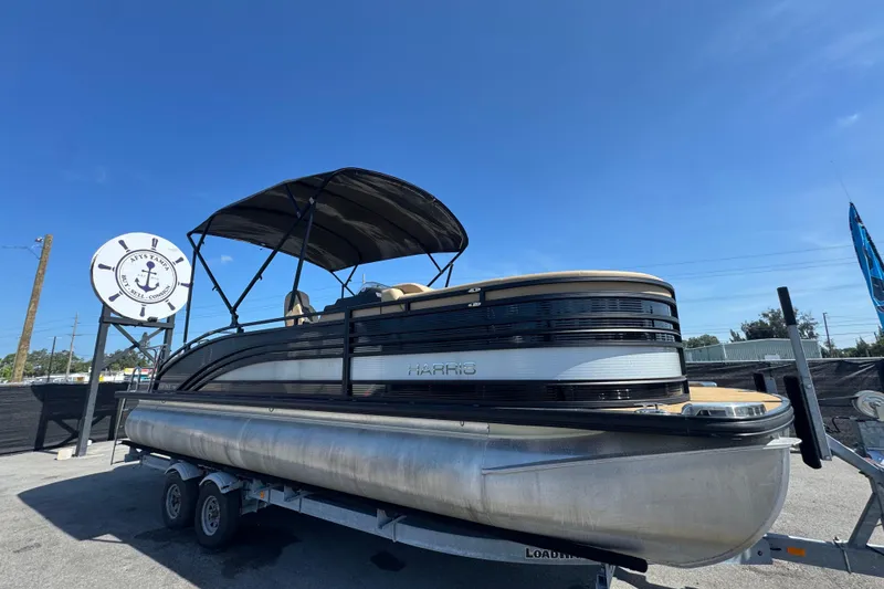 The Image of 2021 Harris Solstice 230 pontoon boat on trailer under clear blue sky. - 0