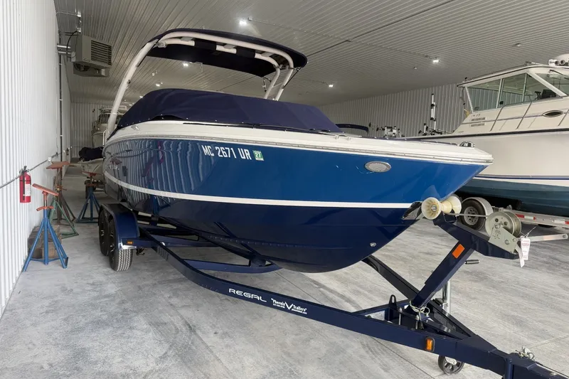 The Image of 2021 Regal LS2 boat in storage, blue hull, on trailer, indoor facility. - 0