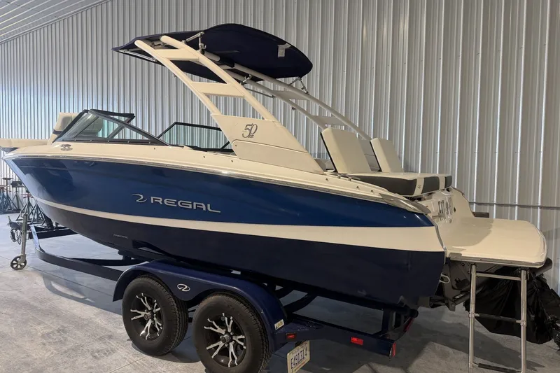 Slide: The Image of 2021 Regal LS2 boat in showroom, blue and white design, on trailer. - 2