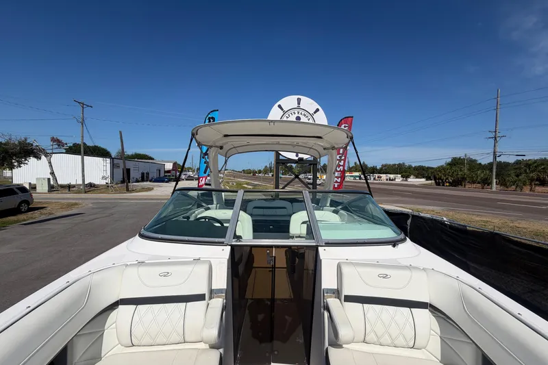 Slide: The Image of 2021 Regal 26 FasDeck boat with white seating, parked outdoors under clear blue sky. - 58