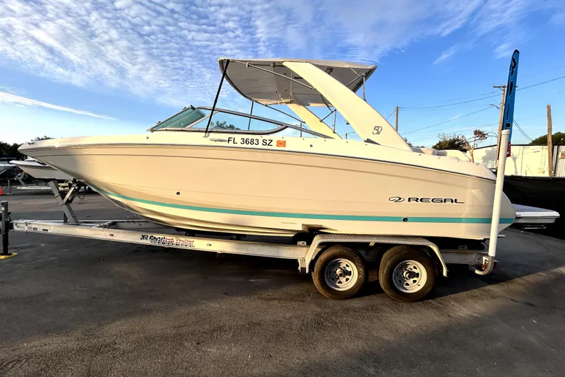 Slide: The Image of 2021 Regal 26 FasDeck boat on trailer under a clear blue sky. - 7