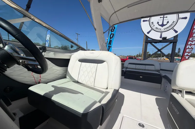 Slide: The Image of 2021 Regal 26 FasDeck boat interior with white seating and steering wheel, under clear blue sky. - 62