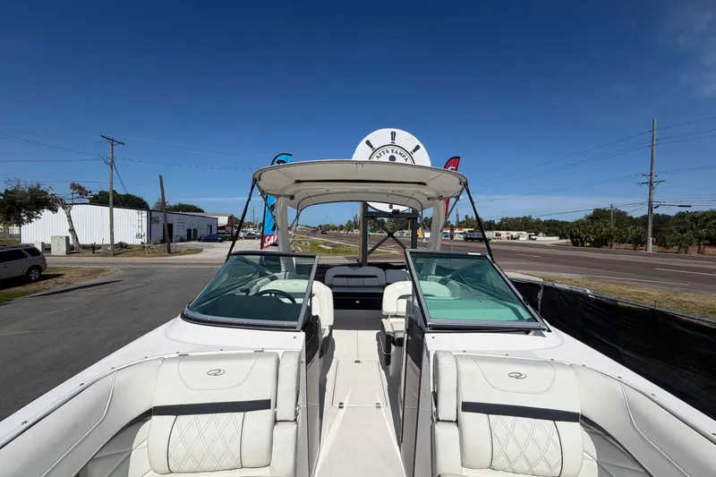 Slide: The Image of 2021 Regal 26 FasDeck boat with white seating, displayed outdoors under clear blue sky. - 57