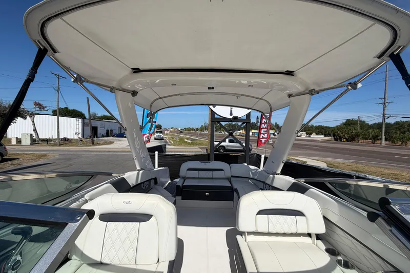 Slide: The Image of 2021 Regal 26 FasDeck boat interior with white seating and canopy, parked outdoors. - 64