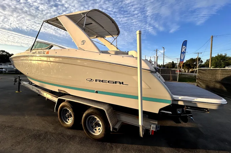 Slide: The Image of 2021 Regal 26 FasDeck boat on trailer under a clear blue sky. - 6