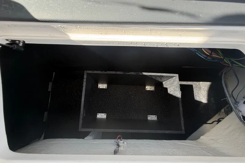 Slide: The Image of Storage compartment in a 2021 Regal 26 FasDeck boat, showing wiring and interior details. - 69