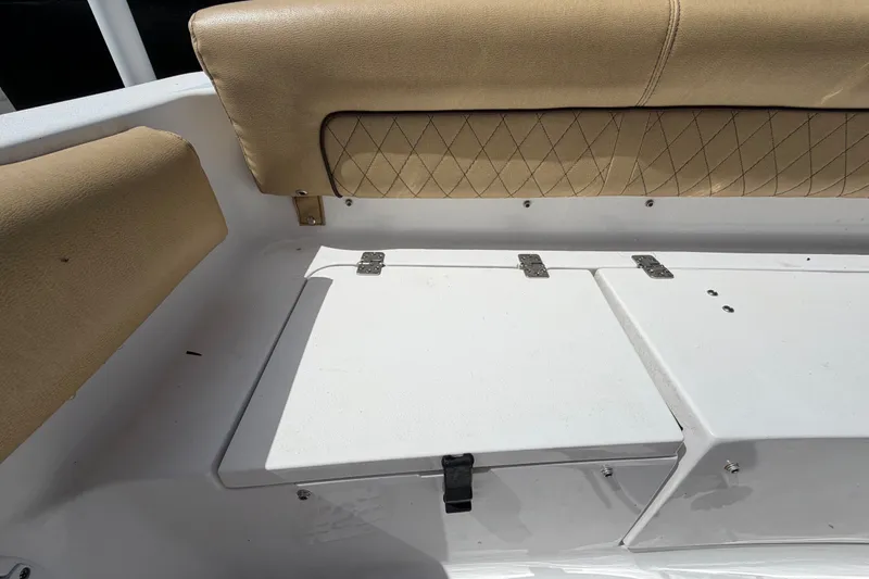 Slide: The Image of 2021 Sportsman Heritage 211 Center Console boat seating with tan upholstery and storage compartment. - 65