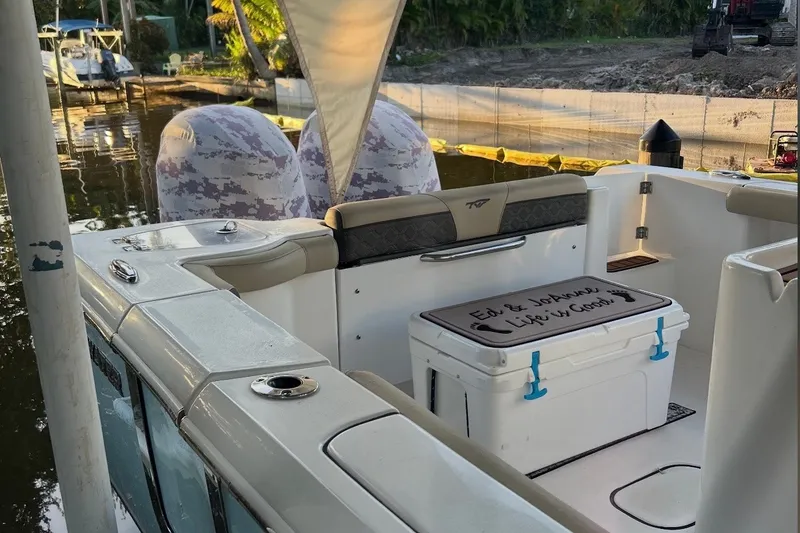 Slide: The Image of 2021 Tidewater 272 CC Adventure boat with cooler, docked by a serene waterfront. - 14