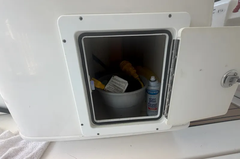 Slide: The Image of Open storage compartment on 2021 Tidewater 272 CC Adventure boat with cleaning supplies. - 43