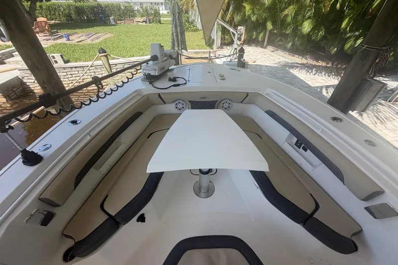 Slide: The Image of 2021 Tidewater 272 CC Adventure boat interior with seating and table, docked near lush greenery. - 22