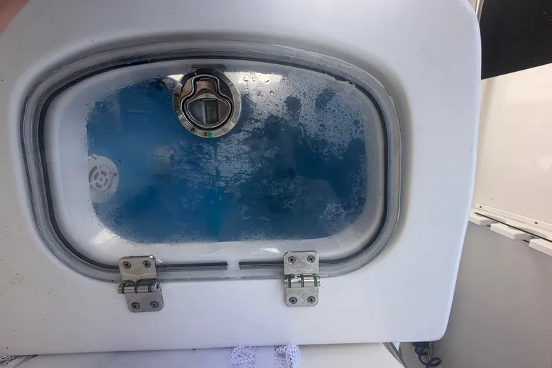 Slide: The Image of Livewell on 2021 Tidewater 272 CC Adventure boat, featuring a transparent lid and latch. - 46
