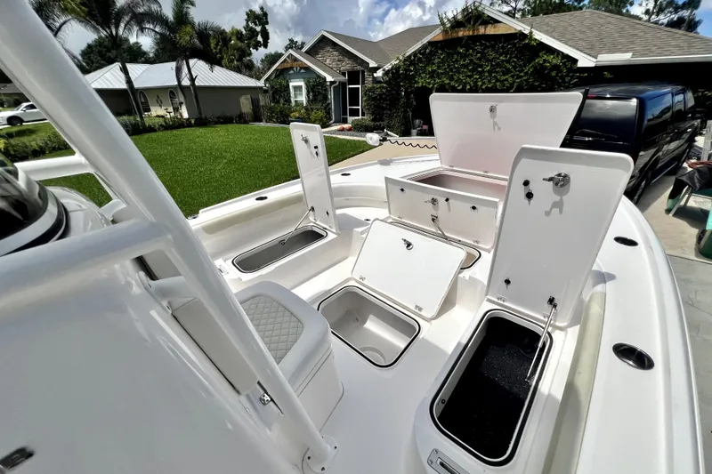 Slide: The Image of 2020 Caymas 26 HB boat with open storage compartments, parked in a residential driveway. - 94