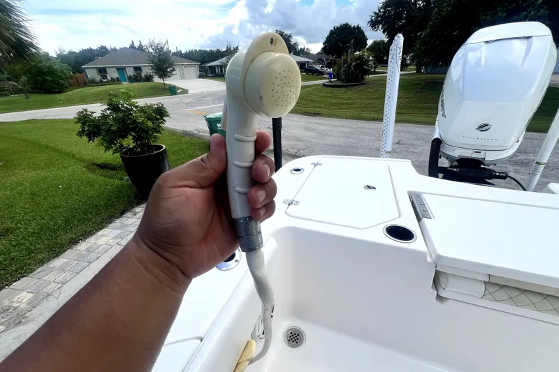 Slide: The Image of Hand holding a showerhead on a 2020 Caymas 26 HB boat deck. - 81