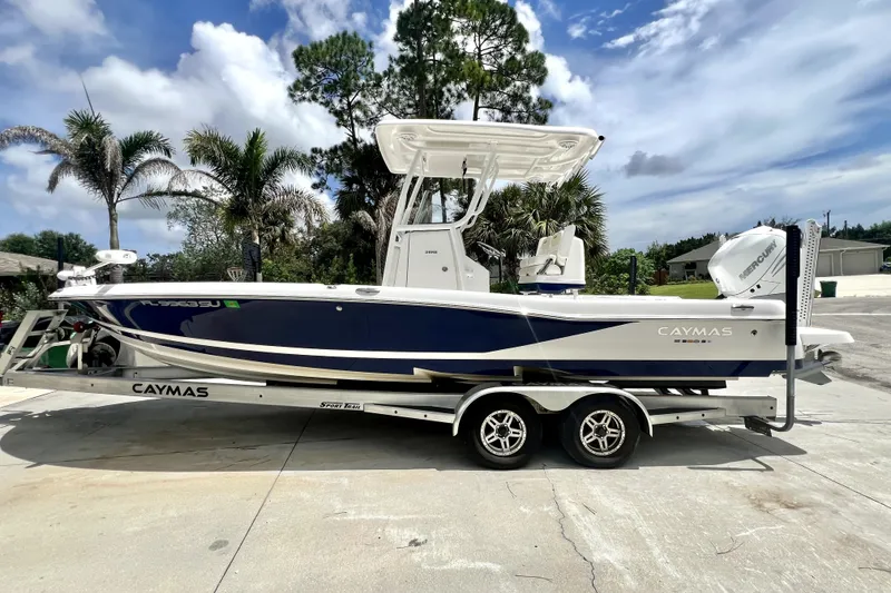 Slide: The Image of 2020 Caymas 26 HB boat on trailer, parked outdoors with palm trees in background. - 1