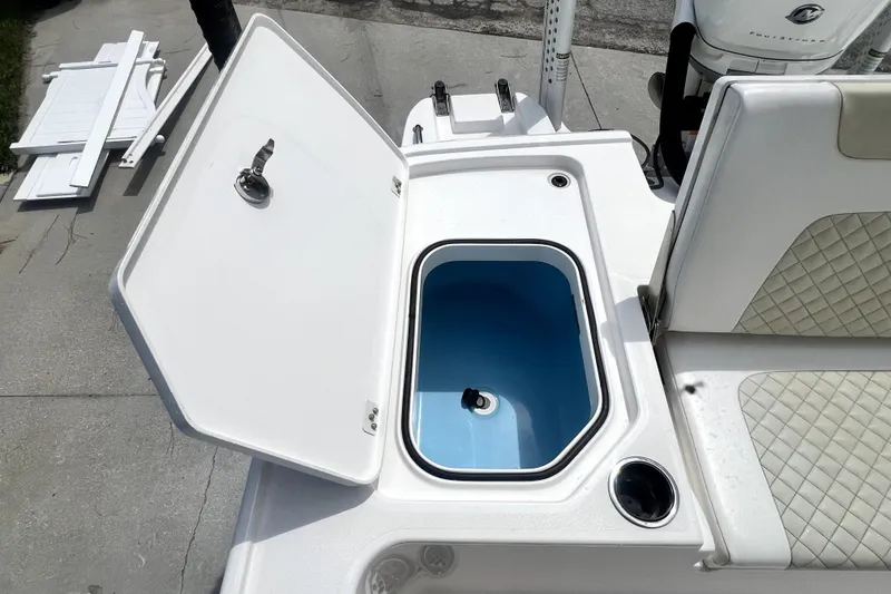 Slide: The Image of 2020 Caymas 26 HB boat with open storage compartment and cushioned seating. - 90