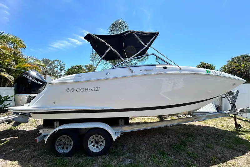 Slide: The Image of 2020 Cobalt 23SC boat on trailer with Mercury engine, parked outdoors. - 1