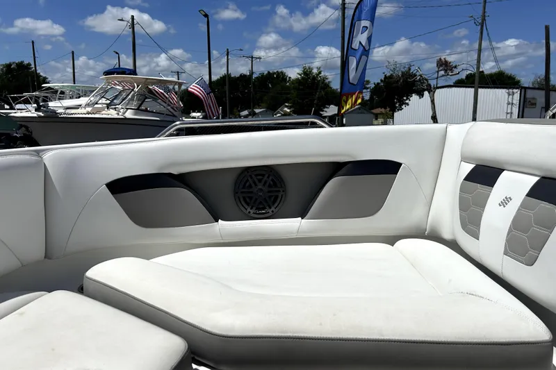 Slide: The Image of 2020 Four Winns HD220 boat interior with white seating and speaker, outdoors under blue sky. - 40
