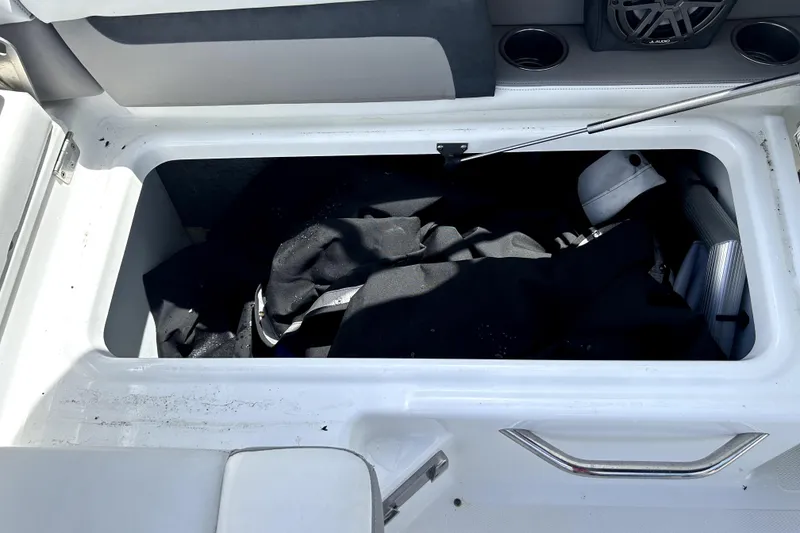 Slide: The Image of Open storage compartment in 2020 Four Winns HD220 boat, containing black fabric and accessories. - 52