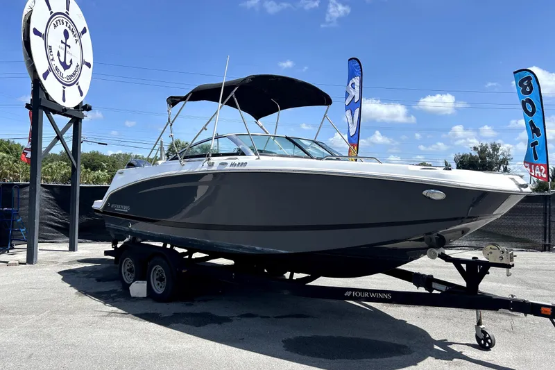 The Image of 2020 Four Winns HD220 boat on trailer at dealership under clear blue sky. - 0