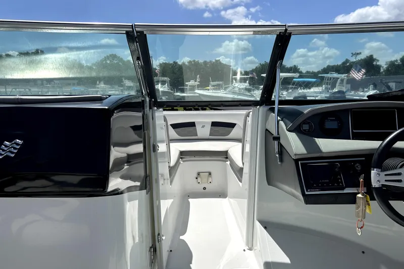 Slide: The Image of 2020 Four Winns HD220 boat interior with dashboard and seating, under a clear blue sky. - 28
