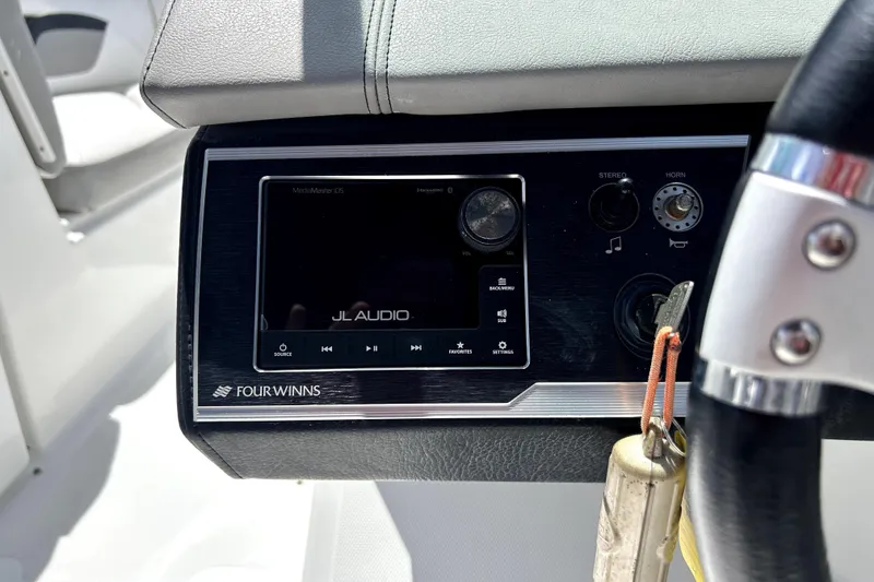 Slide: The Image of 2020 Four Winns HD220 dashboard with JL Audio system and steering wheel. - 22