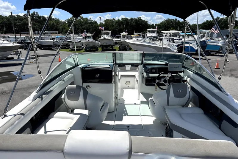 Slide: The Image of 2020 Four Winns HD220 boat interior with seating and steering wheel, docked at a marina. - 14