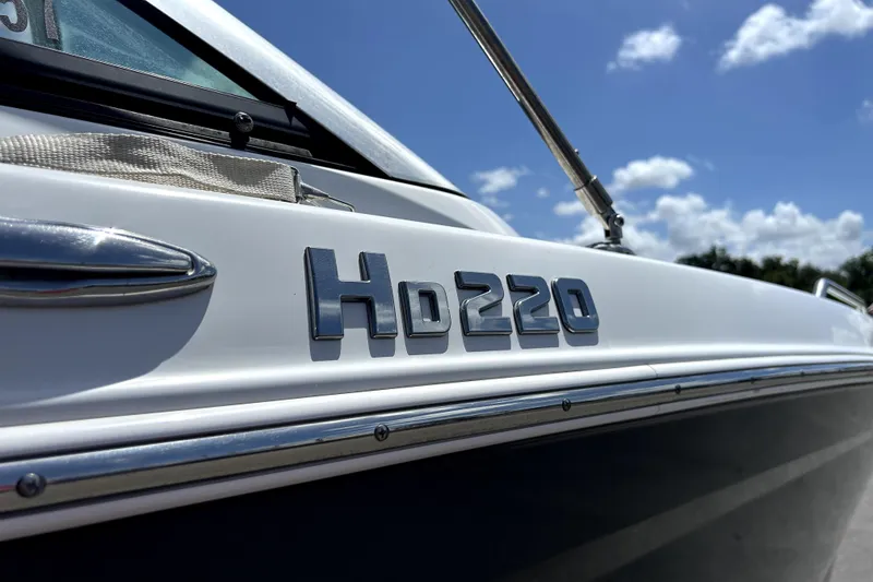 Slide: The Image of 2020 Four Winns HD220 boat exterior with logo under blue sky. - 66