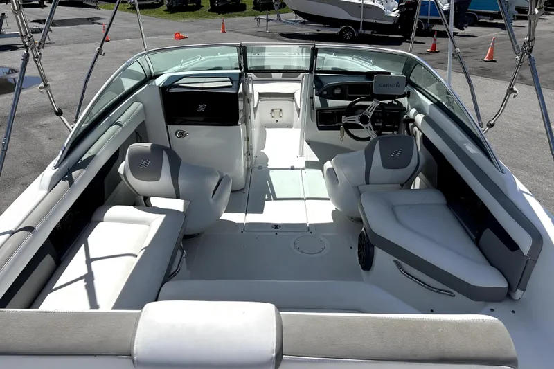 Slide: The Image of 2020 Four Winns HD220 boat interior with seating and steering wheel, parked on pavement. - 13