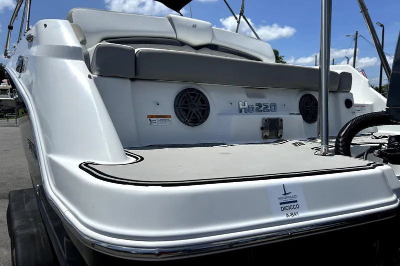 Slide: The Image of 2020 Four Winns HD220 boat rear view with seating and speakers under a clear sky. - 60