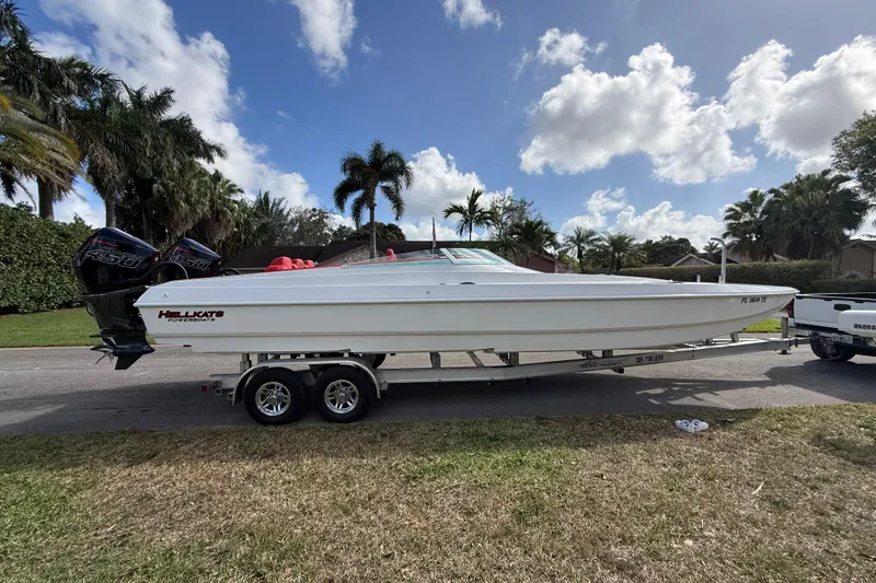 Slide: The Image of 2020 HellKats 30 powerboat on trailer, parked roadside with palm trees in background. - 5