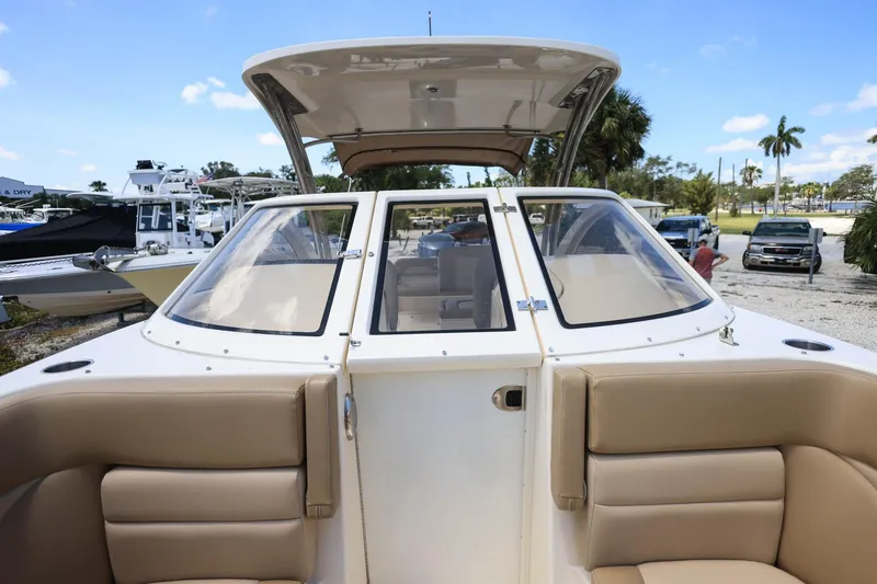Slide: The Image of 2020 Scout 235 Dorado boat with beige seating and windshield, docked outdoors. - 30